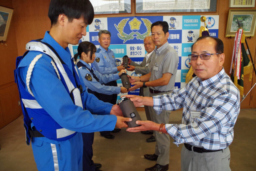 吉川警察署にペットボトルホルダーを手渡す吉川地区警友会の役員ら