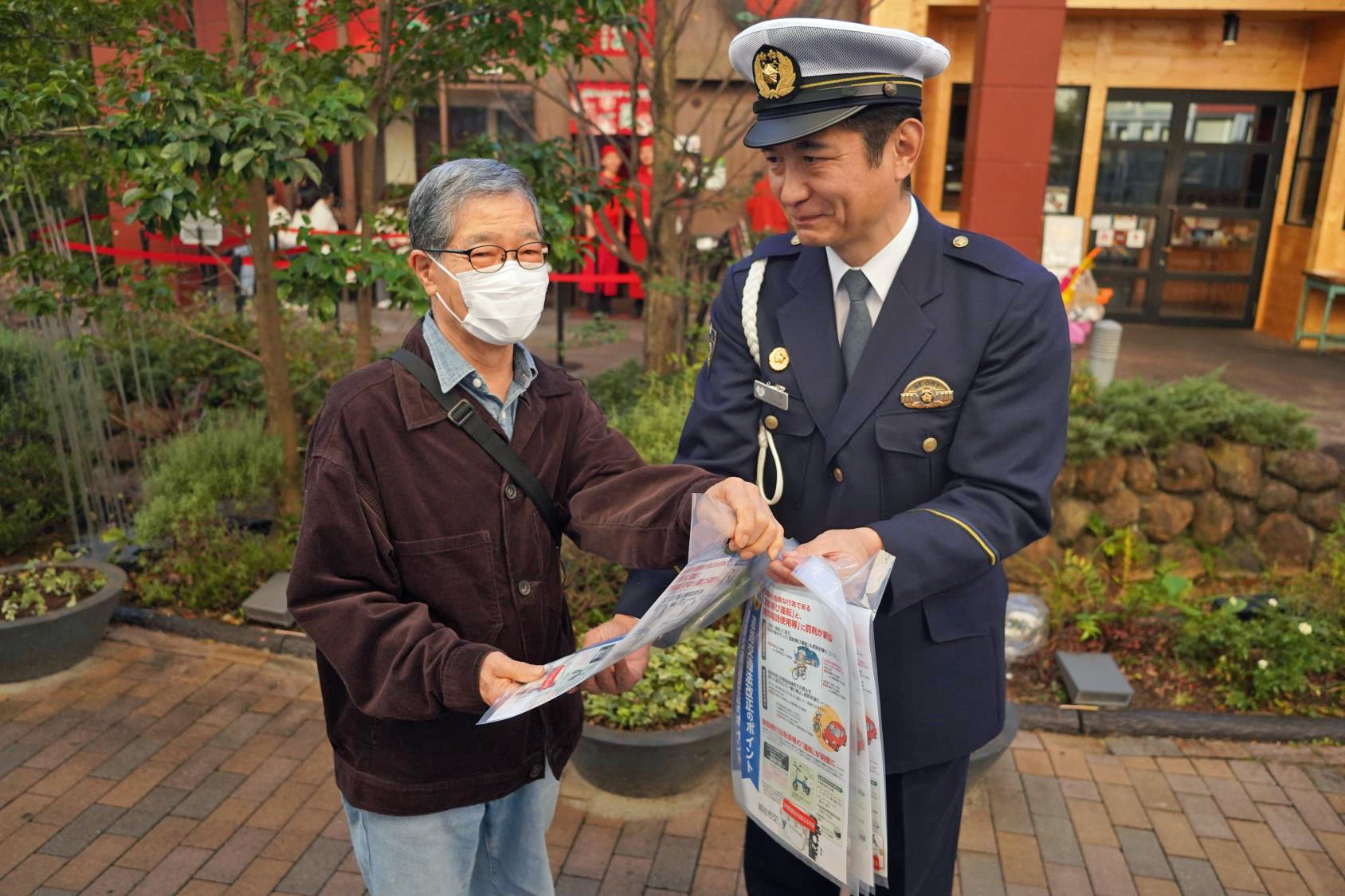 交通事故防止を呼び かける越谷署員（右）